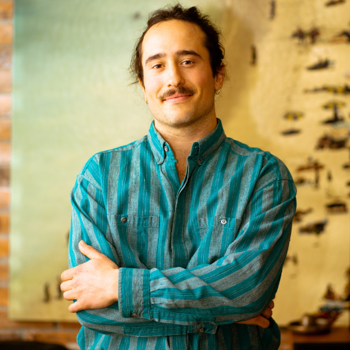 Photo - Digital marketer standing with his arms crosses in front of an art piece.